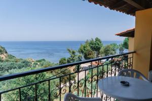 balcón con mesa, sillas y vistas al océano en Celia Apartments, en Vasilikos