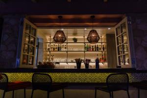 a bar with two chandeliers and a counter with chairs at Celia Apartments in Vasilikos