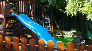 a blue slide in a playground with a wooden fence at Quinta do Paraíso in Porto Martins