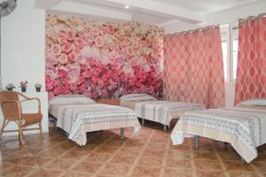 una habitación con 3 camas y una pared con flores en Hostal Ideal Sants, en Barcelona