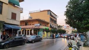 ruchliwa ulica miejska z samochodami zaparkowanymi przed budynkami w obiekcie Unejs Apartment w mieście Berat