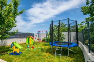 einen Spielplatz mit einem Trampolin im Gras in der Unterkunft Villa "Mile" in Katuni