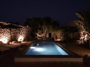 ein Schwimmbad in einem Garten in der Nacht in der Unterkunft Dar Mayssoun in Ghazoua