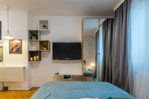 um quarto com uma cama e uma televisão na parede em Merci Apartment em Belgrado