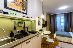 uma cozinha com um lavatório e um quarto com uma cama em Merci Apartment em Belgrado