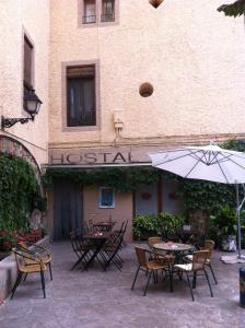 un patio extérieur avec des tables, des chaises et un parasol dans l'établissement Hostal Victor, à Oliana