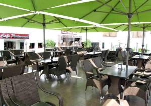 um restaurante vazio com mesas e cadeiras com guarda-sóis verdes em Suite Hotel Tilila em Agadir