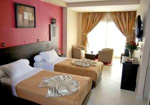 two beds in a hotel room with red walls at Suite Hotel Tilila in Agadir