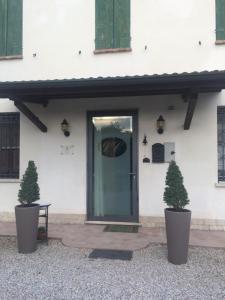 a front door of a white building with two potted trees at Agriturismo Loghino Caselle in San Giorgio Di Mantova