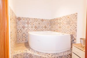 La salle de bains est pourvue d'une baignoire et d'un mur en carrelage. dans l'établissement CASA STESICORO, à Catane