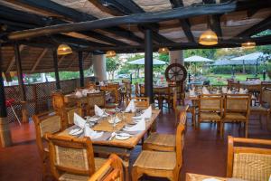 ein Restaurant mit Holztischen, Stühlen und Sonnenschirmen in der Unterkunft Kambiri Beach by Serendib in Senga