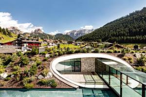 uma casa numa colina com vista para as montanhas em Hotel Alpenroyal - The Leading Hotels of the World em Selva di Val Gardena