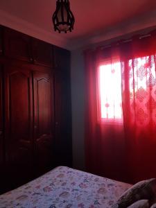 a bedroom with a bed and a window with red curtains at Location Vacances Casablanca Tamaris in Casablanca