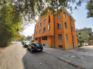 pomarańczowy budynek z samochodami zaparkowanymi przed nim w obiekcie Appartamento Venezia w mieście Marghera
