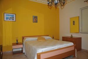 a bedroom with a bed and a yellow wall at Villa Grazia in Noto Marina