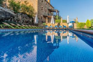 a swimming pool with umbrellas and chairs and a pool at Casa rural Sant Grau turismo saludable y responsable in Solsona