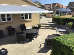 a patio with a table and chairs and a building at Langø Overnatning in Langø