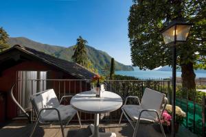 eine Terrasse mit einem Tisch, Stühlen und einer Lampe in der Unterkunft Romantic Bijou in Lugano