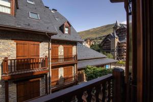 een balkon van een huis met houten deuren en balkons bij TAMARRO de Alma de Nieve in Baqueira-Beret