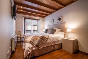 a bedroom with a bed and a tv and a window at TAMARRO de Alma de Nieve in Baqueira-Beret