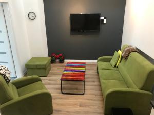 a living room with two green couches and a tv at Klimatyczny apartament przy bocheńskim Rynku. in Bochnia