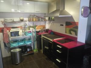 a kitchen with a stove and a red counter top at LA LOBERA (VALLE DEL TIETAR) in La Iglesuela