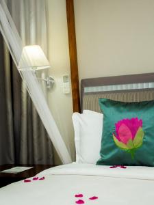 a bed with a green pillow with a pink flower on it at Serendib Suites and Conference Center in Blantyre