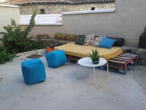 a patio with a bed and a table and blue chairs at LA LOBERA (VALLE DEL TIETAR) in La Iglesuela