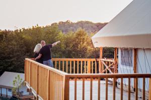 un hombre y una mujer parados en la cubierta de una casa en ForRest Glamping en Banská Štiavnica