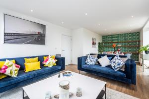 un soggiorno con divani blu e TV di Chiswick Park Apartments London a Londra