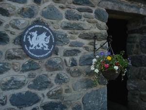 a sign on a stone wall with a basket of flowers at Ystumgwern Luxury Barn Conversions in Dyffryn
