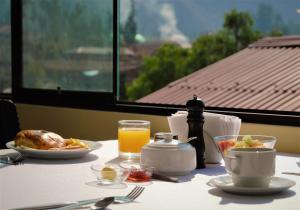 a table with a plate of food and a glass of orange juice at Hotel Andes Urubamba by Ämak in Urubamba