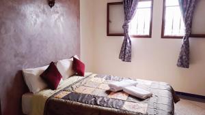 a bedroom with a bed in a room with windows at Asklou Appartement à Mirleft in Mirleft
