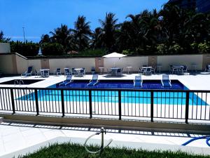 a swimming pool with tables and chairs next to a fence at Marbella Apart Hotel in Rio de Janeiro