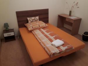 1 cama grande de color naranja con 2 toallas en Piac utcai Apartman, en Debrecen