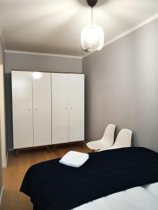 a bedroom with a bed and two white chairs at CENTRAL PARK Apartment in Zielona Góra