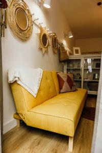 um sofá amarelo numa sala de estar com espelhos na parede em Amoreira em Setúbal