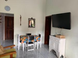 a living room with a television and a table with chairs at Vila Colorida casa 2 in Fazendinha