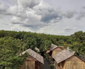 Tribal Village Homestay & Trekking في راتاناكيري: اطلالة علوية على مجموعة اكواخ اشجار