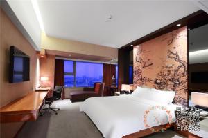Habitación de hotel con cama blanca grande y escritorio. en Grand Mercure Dongguan Humen, en Dongguan