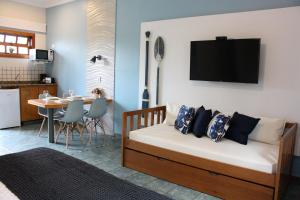 a living room with a bed and a kitchen with a table at Suite Ilhaflat in Ilhabela