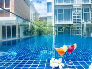 einen Pool mit zwei Cocktails und Blumen darüber in der Unterkunft Glenwood City Resort in Ho-Chi-Minh-Stadt