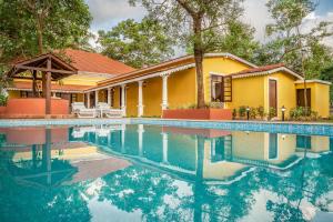 une maison avec une piscine en face de celle-ci dans l'établissement amã Stays & Trails, Cardozo House, à Candolim