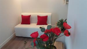 Una cama con almohadas rojas y un jarrón con flores rojas. en Paris 8 ème Appartement 2 pièces Métro Miromesnil, en París
