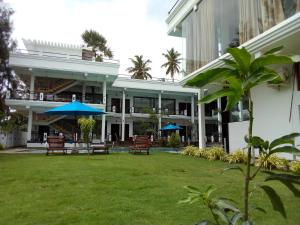 a building with chairs and blue umbrellas in a yard at J7 Villaj Resort in Trincomalee