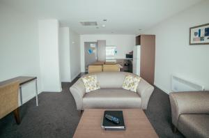 a living room with a couch and a chair at Airport Delta Motel in Christchurch