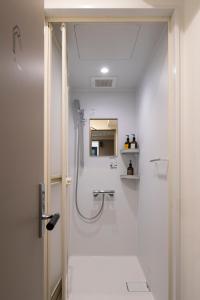 a white bathroom with a shower and a sink at Grids Tokyo Ueno Hotel&Hostel in Tokyo