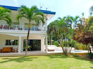 una casa con palmeras delante en Luxury Villa with Pool in Tropical Garden, en Puerto Princesa City