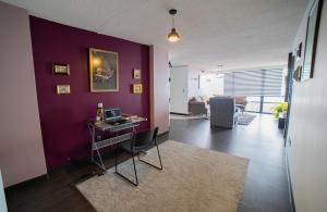 a living room with a purple wall and a desk at Caravansaro Penthouse Polanco in Mexico City