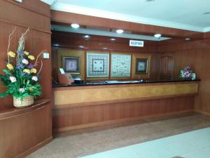una sala de espera con caja registradora y flores en Sara Hotel, en Labuan